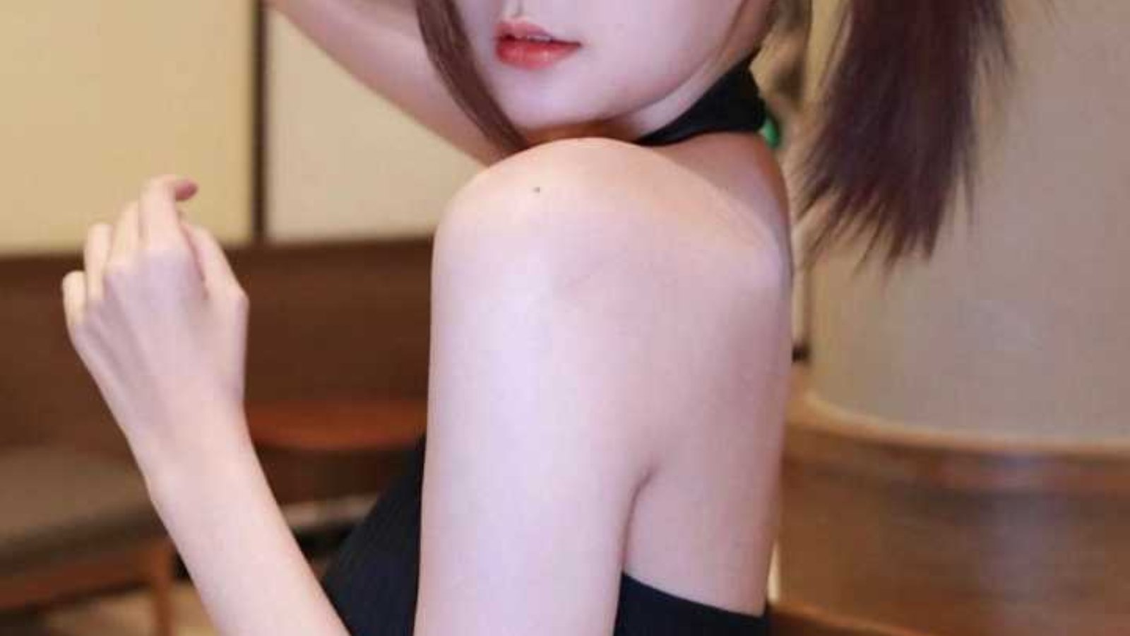 Attractive young woman with brown hair styled in a ponytail, wearing a black halter top.