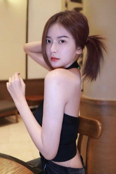 Attractive young woman with brown hair styled in a ponytail, wearing a black halter top.