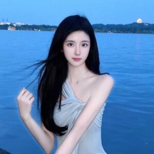 Young woman with long black hair by a lake at dusk.