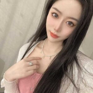 Portrait of a young woman with long dark hair wearing a pink top and a pearl necklace.