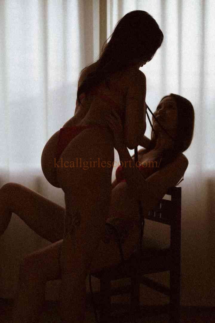 Silhouette of two women in lingerie, one sitting on a chair, the other standing behind her.